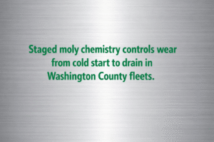 Minimalist vector graphic with gunmetal background and bright metallic green text reading “Staged moly chemistry controls wear from cold start to drain in Washington County fleets.” 